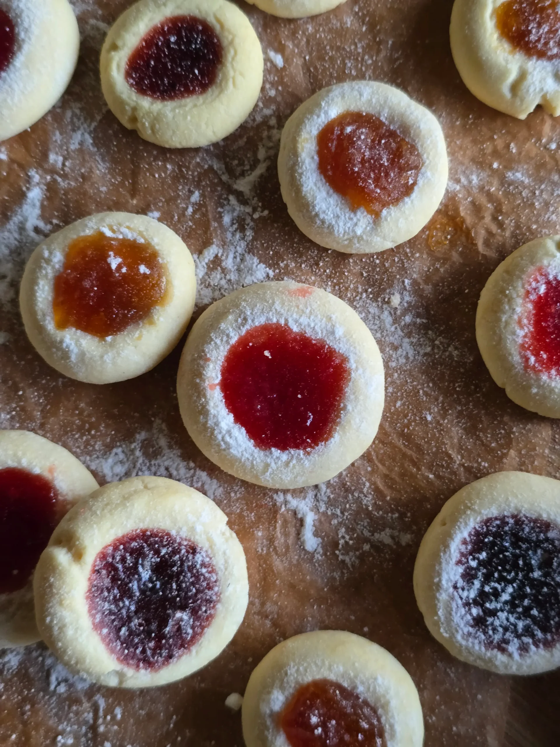 Jam thumbprint cookies: Freshly baked with bright red jam centers cooling on a baking sheet.