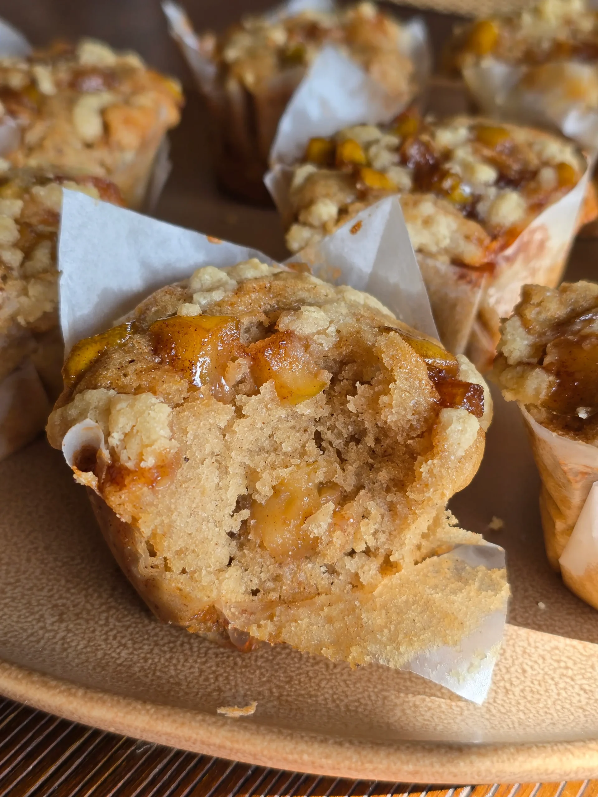 Freshly baked apple cinnamon muffins cooling on a rack, golden brown and sprinkled with a light dusting of cinnamon sugar.