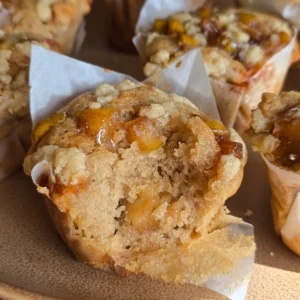 Freshly baked apple cinnamon muffins cooling on a rack, golden brown and sprinkled with a light dusting of cinnamon sugar.