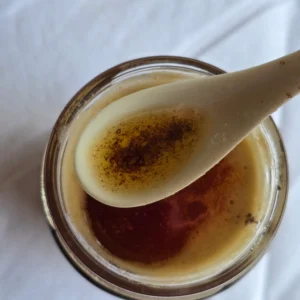 Golden browned butter cooling in a glass jar.