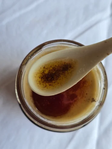 Golden browned butter cooling in a glass jar.